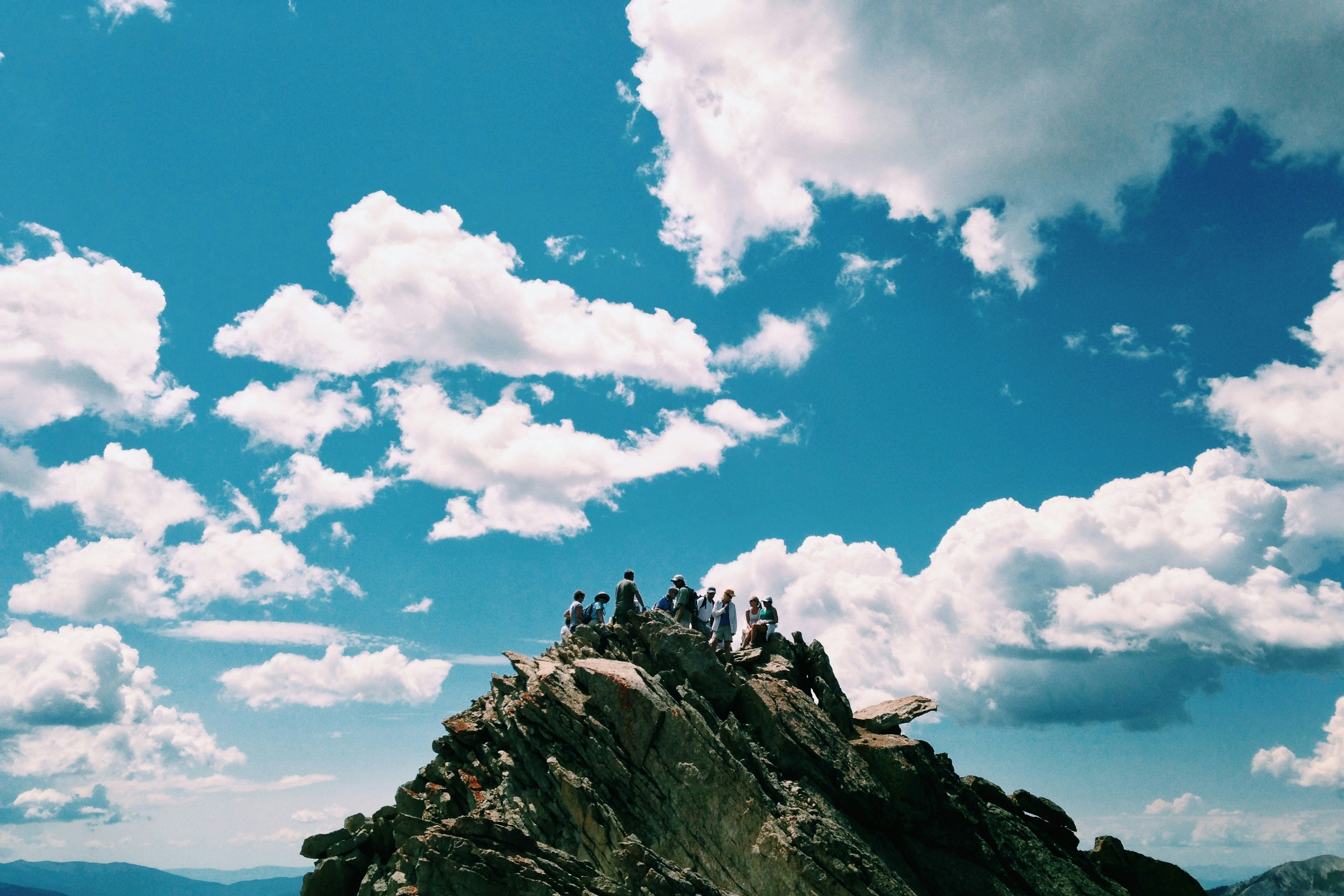 A group of people sat on top of a rocky outcrop.